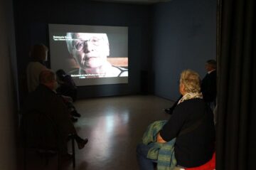 Besucherinnen und Besucher schauen das Zeitzeugenvideo
