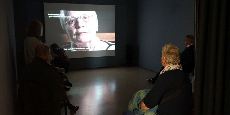Besucherinnen und Besucher schauen das Zeitzeugenvideo