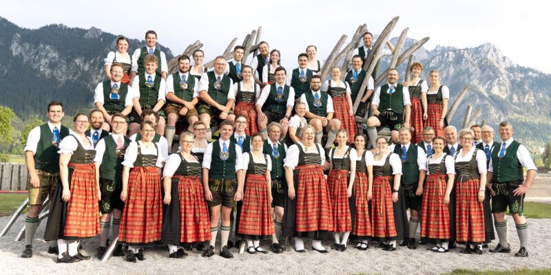 Eine Gruppe von Männern und Frauen in Dirndl und Tracht vor den Bergen
