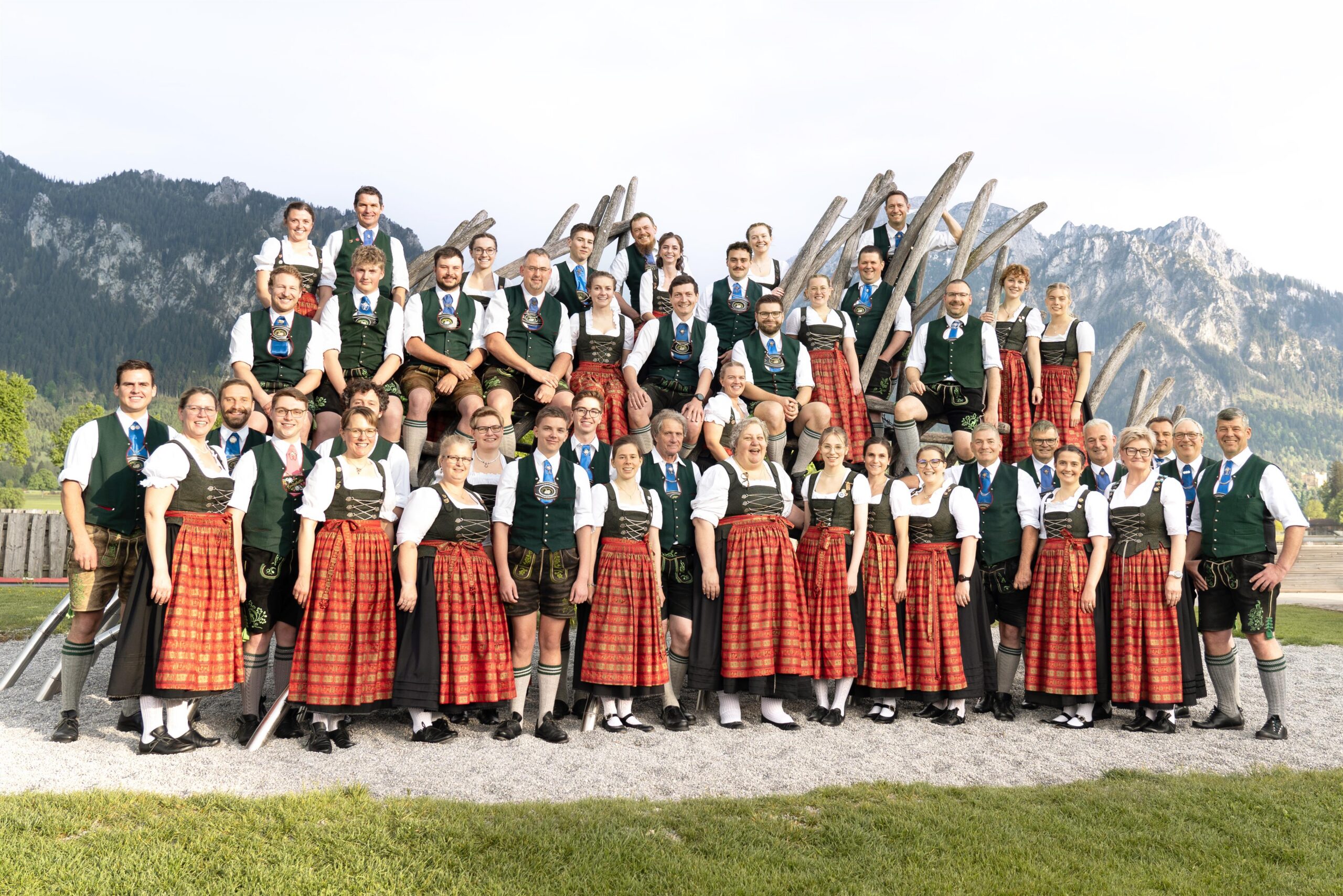 Musikkapelle Schwangau Eine Gruppe von Männern und Frauen in Dirndl und Tracht vor den Bergen